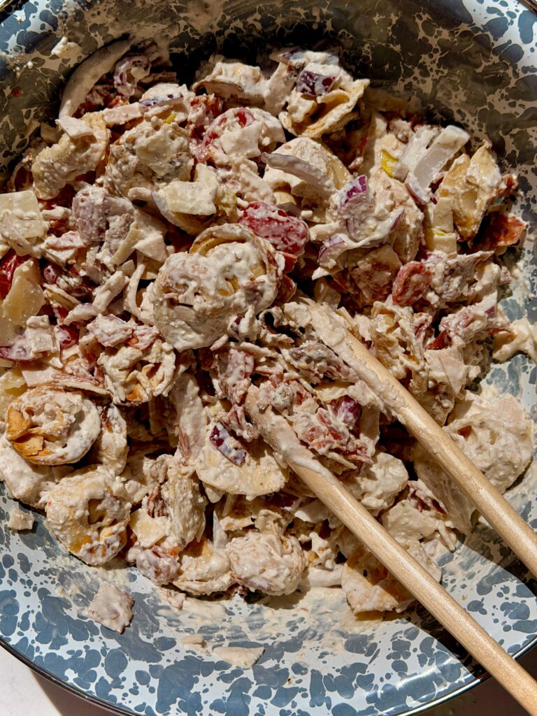 grinder pasta salad with crispy air fryer tortellini, deli turkey, salami, bacon, pepperoncini, and shaved parmesan in a white bowl