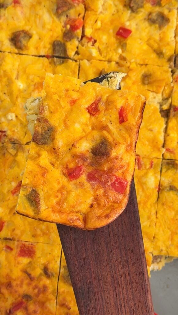 Maple sausage egg bake with cheddar and hashbrowns sliced in a baking dish