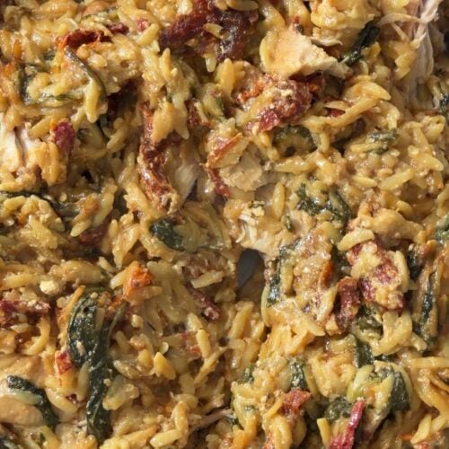 Creamy tuscan chicken orzo bake with spinach and sun dried tomatoes in a baking dish