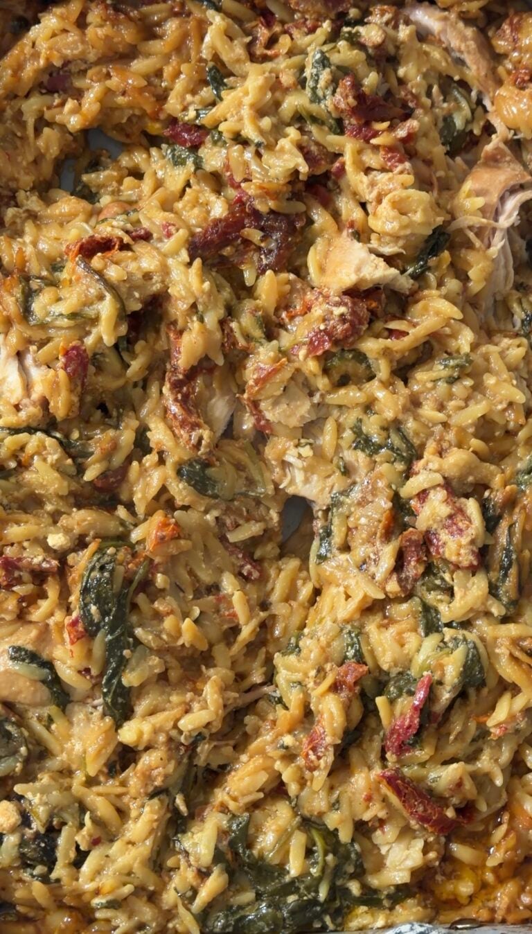 Creamy tuscan chicken orzo bake with spinach and sun dried tomatoes in a baking dish