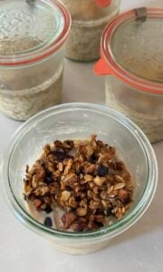 A jar of apple crisp overnight oats layered with cinnamon apples and topped with a crunchy oat pecan crisp topping