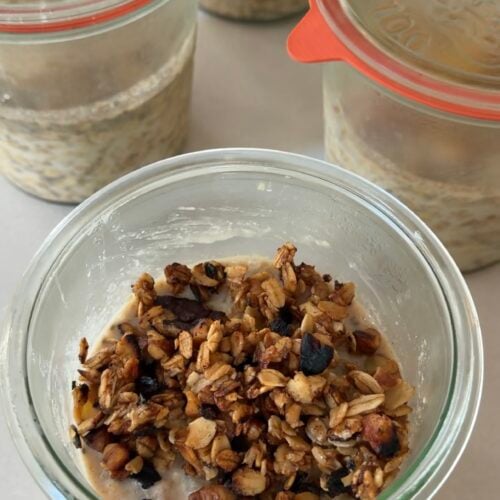 A jar of apple crisp overnight oats layered with cinnamon apples and topped with a crunchy oat pecan crisp topping